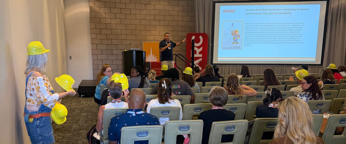 Attendees wearing yellow hard hats listen to Bob Rojee present the Bob the Builder workshop at SPARC 2026.
